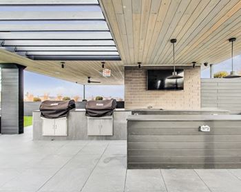 the outdoor patio has a tv and two bar stools